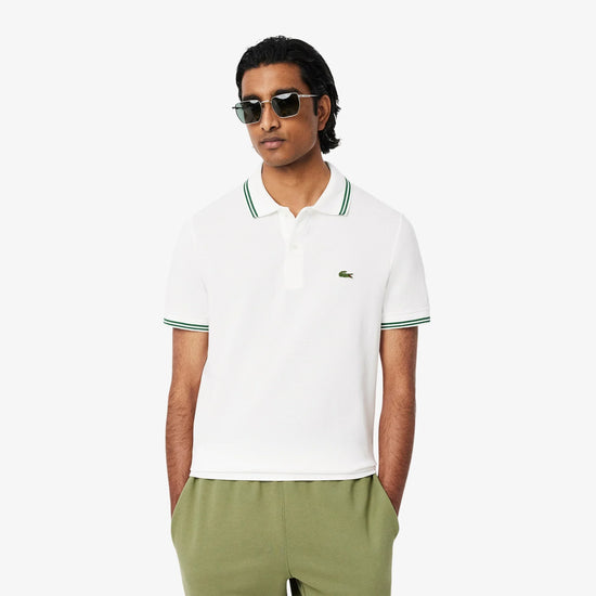 Man i vit pikétröja med gröna detaljer och solglasögon, herrmode, neutral bakgrund
