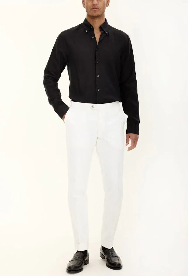 Man i svart linneskjorta och vita byxor, klassiska herrkläder med eleganta loafers
