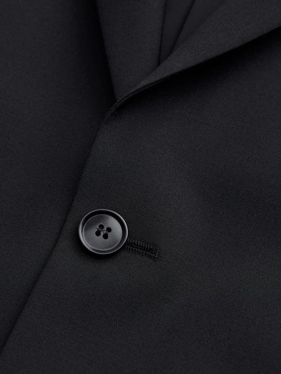 Närbild av svart kostymkavaj med knapp, klassiskt herrmode, exklusivt tyg