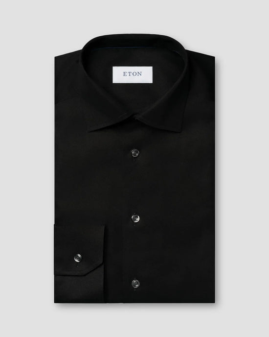 Svart herrskjorta i twill, klassisk modell med knappar och krage, vikt på ljus bakgrund.