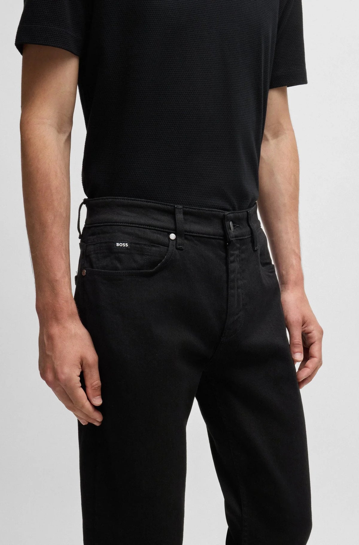 Herr i svart pikétröja och svarta jeans, modern stil, närbild på byxor