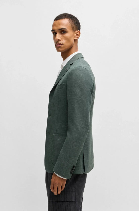 Man i grön blazer och vit skjorta, klassiskt herrmode, stående mot ljus bakgrund