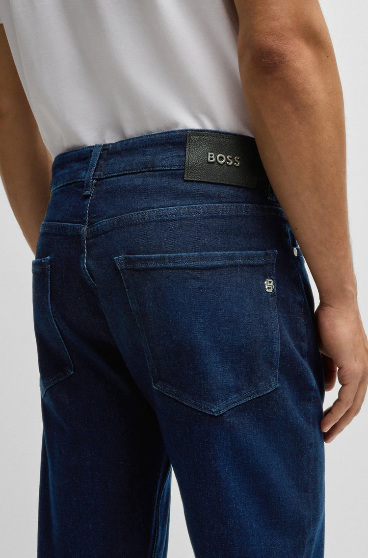 Blå herrjeans med bakfickor och svart BOSS-logotyp, bärs med vit t-shirt