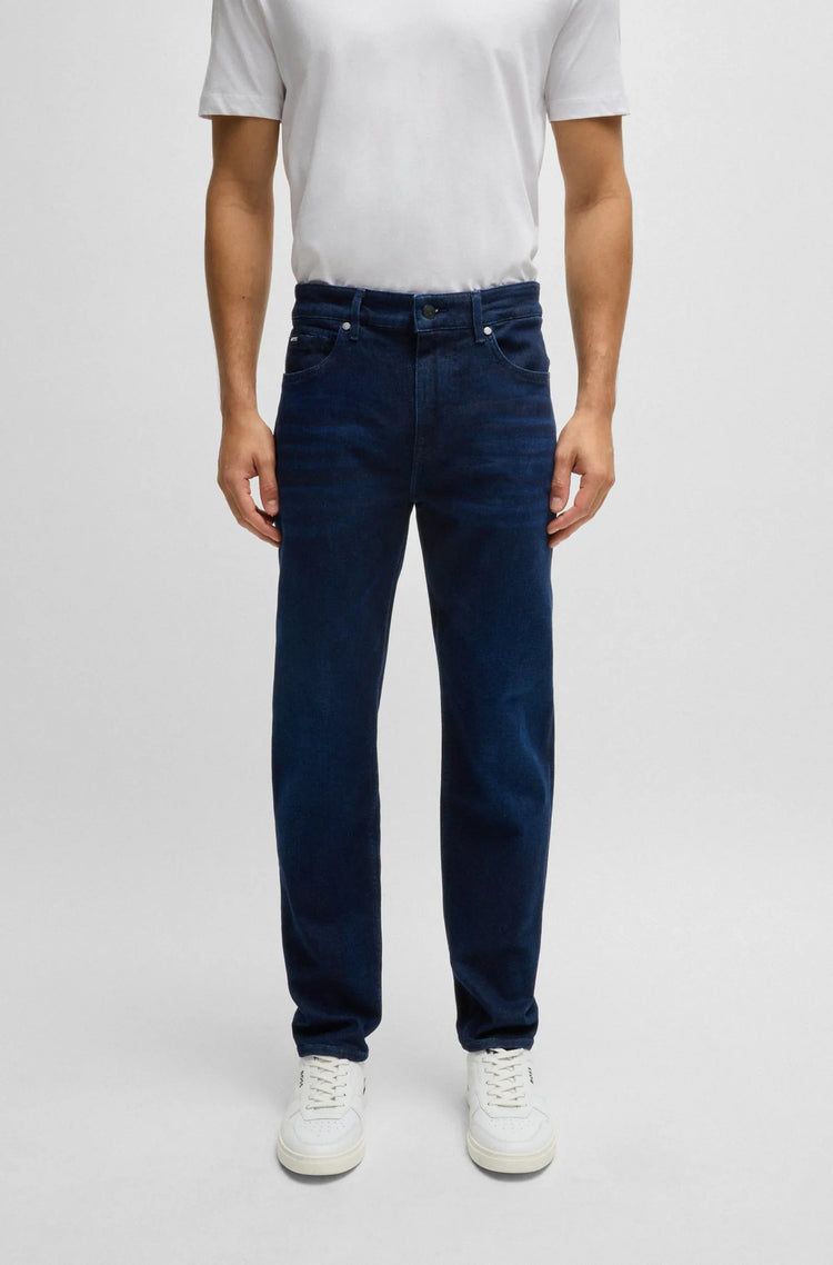 Man i mörkblå raka jeans och vit t-shirt, casual herrkläder mot ljus bakgrund