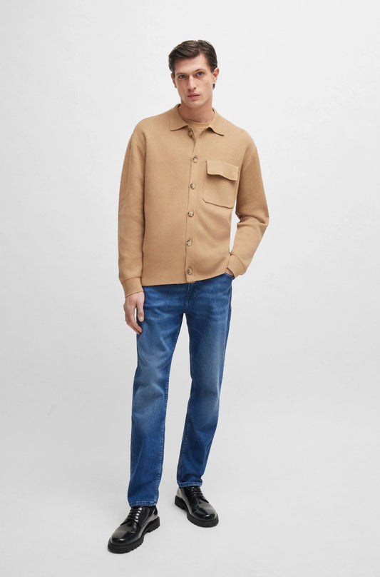 Man i beige skjortjacka, blå jeans och svarta skor, klassisk herrstil