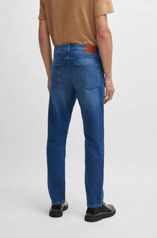 Herrkläder, klassiska blå jeans bakifrån med fickor, bärs av man i beige t-shirt