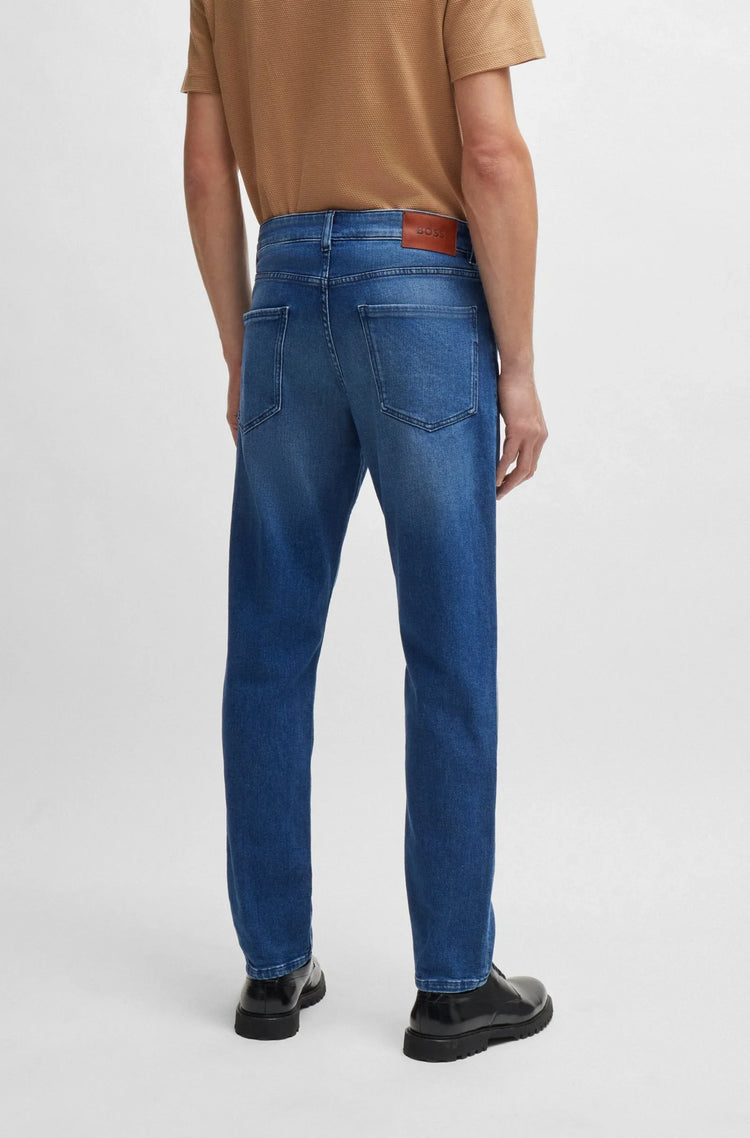 Herrkläder, klassiska blå jeans bakifrån med fickor, bärs av man i beige t-shirt