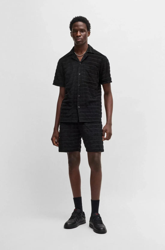 Man i svart kortärmad skjorta och shorts, herrmode, enkel bakgrund