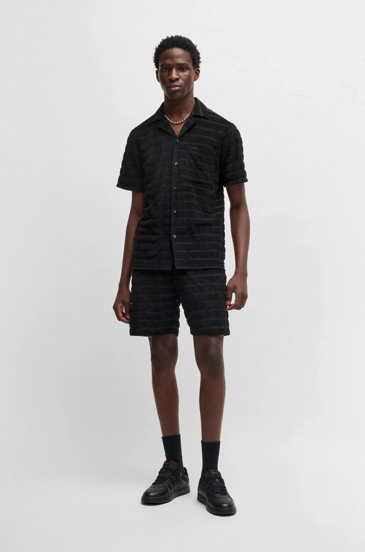 Man i svart kortärmad skjorta och shorts, herrmode, enkel bakgrund