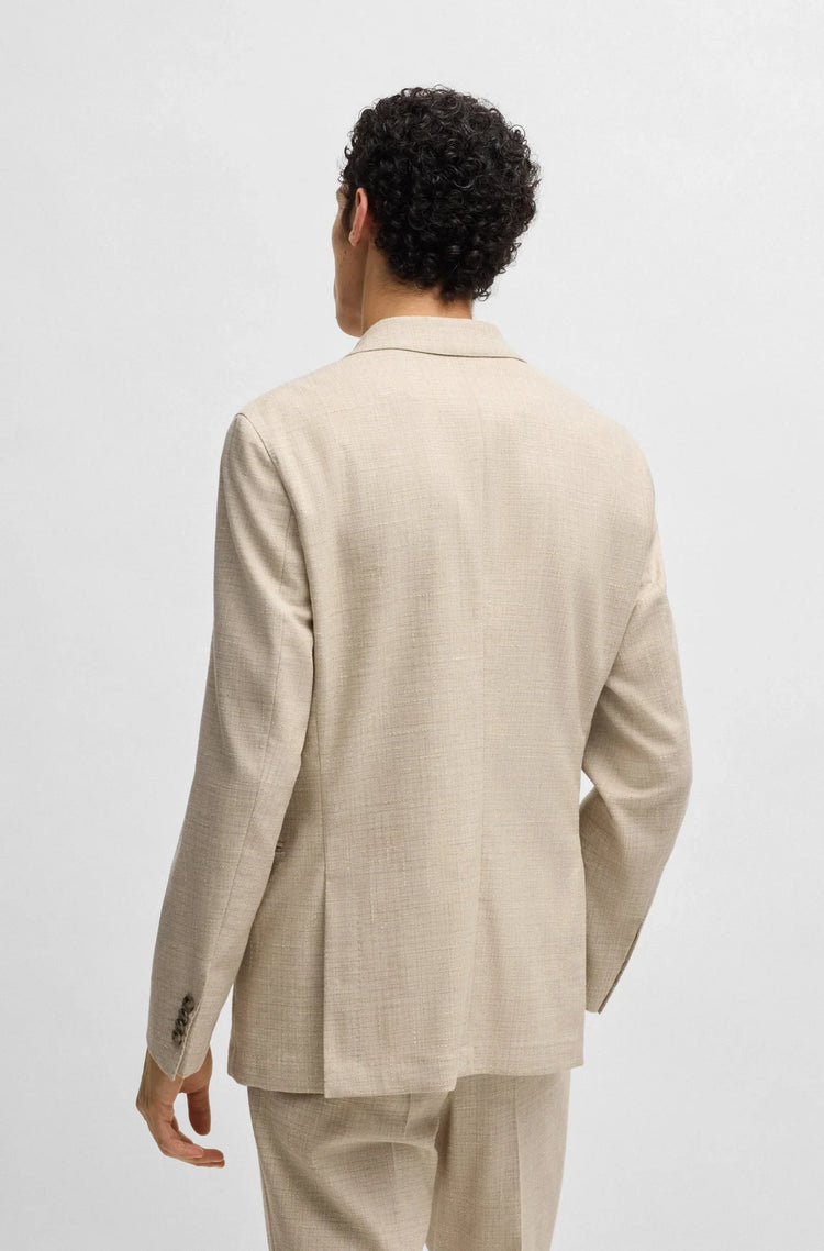 Man i beige kostym, sett bakifrån, klassiska herrkläder mot ljus bakgrund