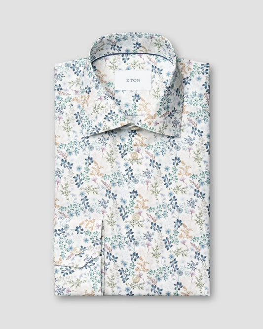 Herrskjorta i vit twill med blått blommönster, vikt och knäppt framtill.