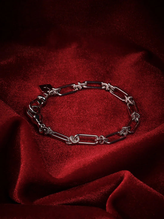 Snyggt herrarmband i silver med detaljer, presenterat på röd sammetstyg.