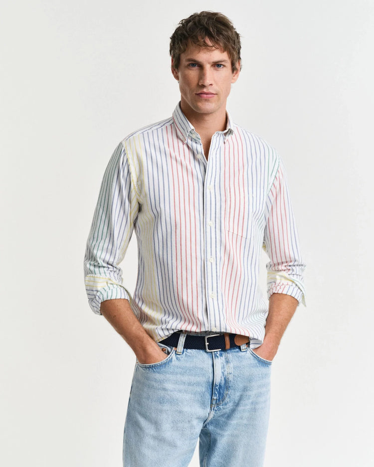 Man i randig skjorta och ljusa jeans, klassiskt herrmode mot vit bakgrund.