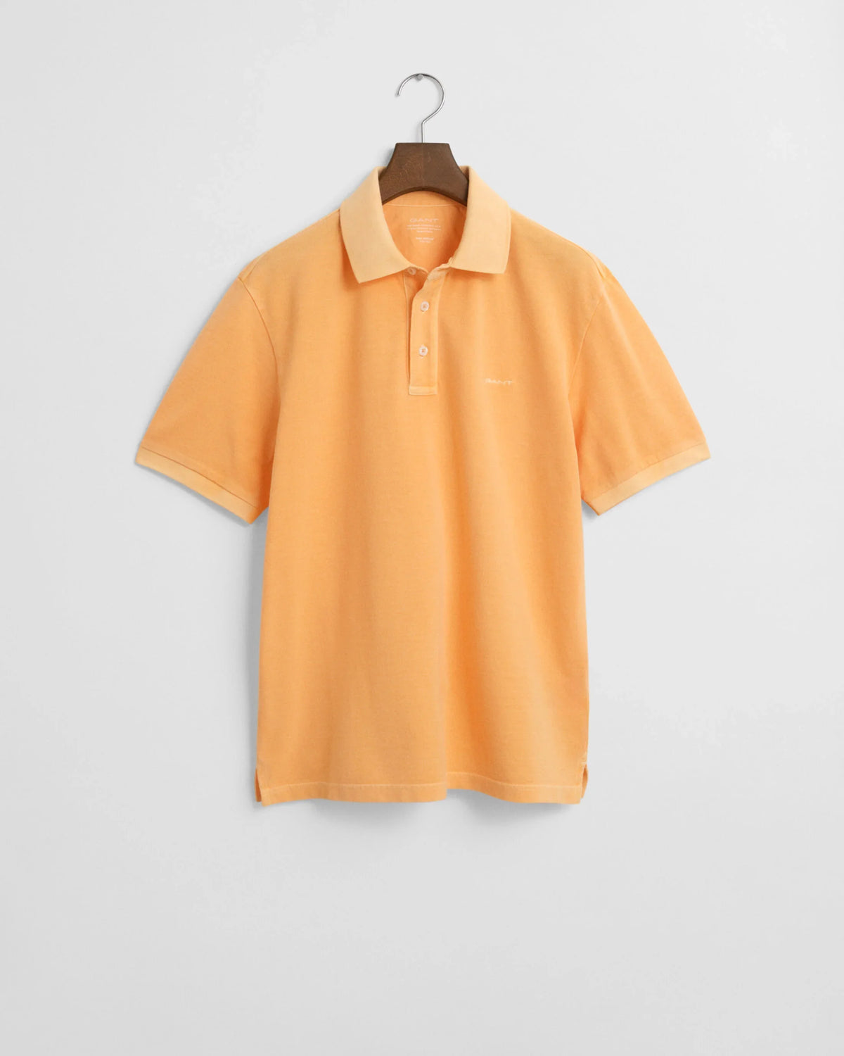 Kortärmad orange pikétröja för herr med klassisk krage, hängande mot vit bakgrund.