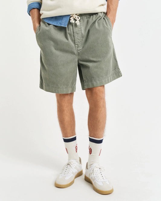 Herrmodell bär gröna shorts med dragsko, vita sneakers och vita sportstrumpor