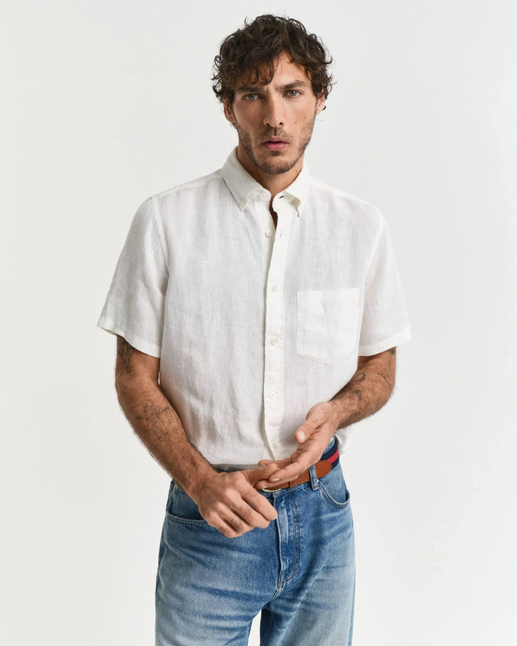 Man i vit linneskjorta med kort ärm och blå jeans mot vit bakgrund