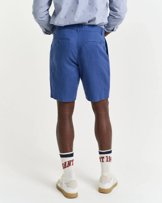 Man i blå herrshorts och mönstrad skjorta, vita strumpor och sneakers, bakifrån