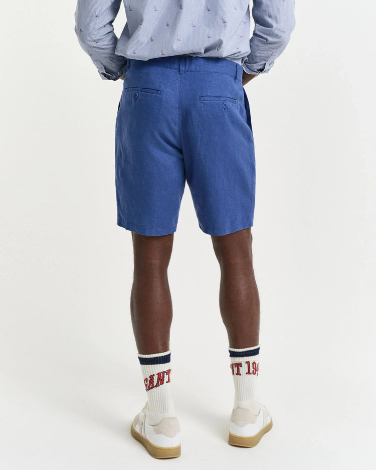 Man i blå herrshorts och mönstrad skjorta, vita strumpor och sneakers, bakifrån