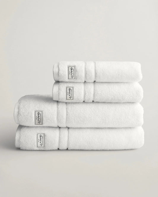 Vita handdukar i frotté staplade på varandra mot ljus bakgrund, herrtextil och accessoar.