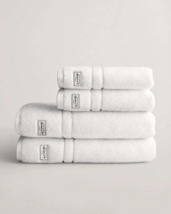 Vita handdukar i frotté staplade på varandra mot ljus bakgrund, herrtextil och accessoar.