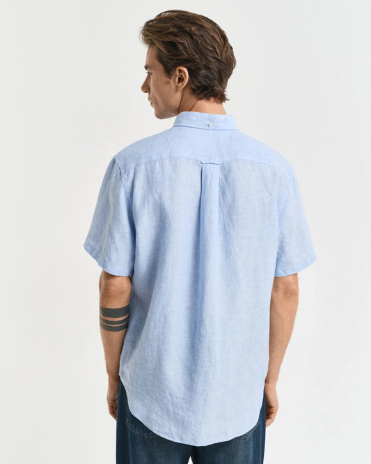 Man bär ljusblå linneskjorta med kort ärm och jeans, visad bakifrån mot vit bakgrund.