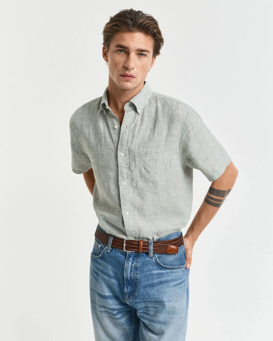 Man i ljusgrön linneskjorta med kort ärm och blå jeans, klassisk herrstil
