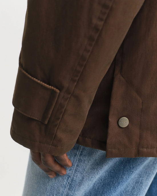 Brun herr jacka med knappdetalj och ficka, bärs med ljusblå jeans