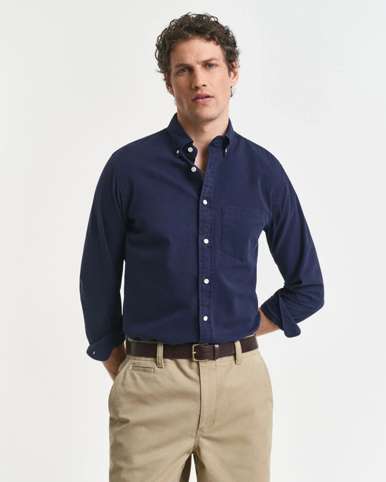 Man i klassisk marinblå skjorta och beige chinos, herrmode med stilren design.