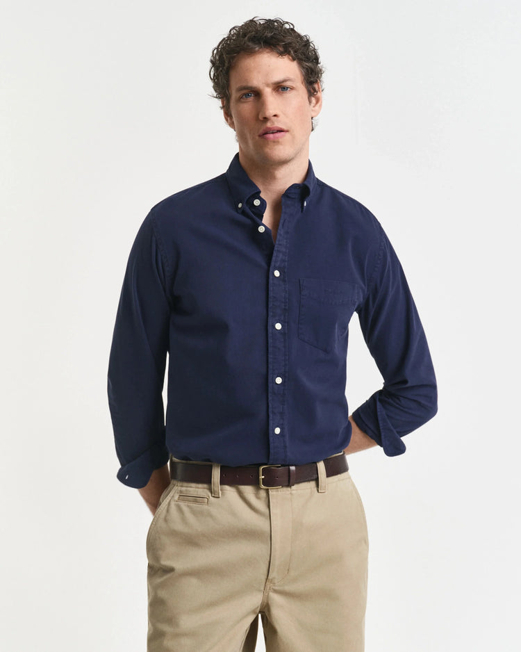 Man i klassisk marinblå skjorta och beige chinos, herrmode med stilren design.