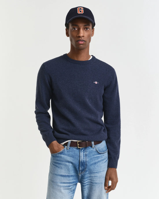 Mörkblå herr tröja med rund hals och jeans, modell bär mörkblå keps.