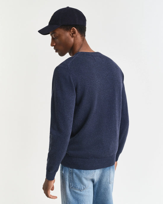 Marinblå herr tröja – Holmens Herr, stickad tröja, modell bakifrån, jeans, keps