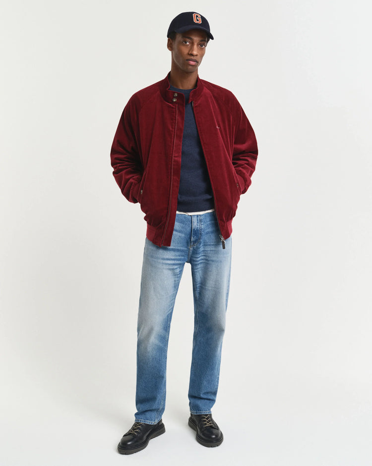 Modell bär herr jacka, röd, med jeans och mörka skor mot vit bakgrund