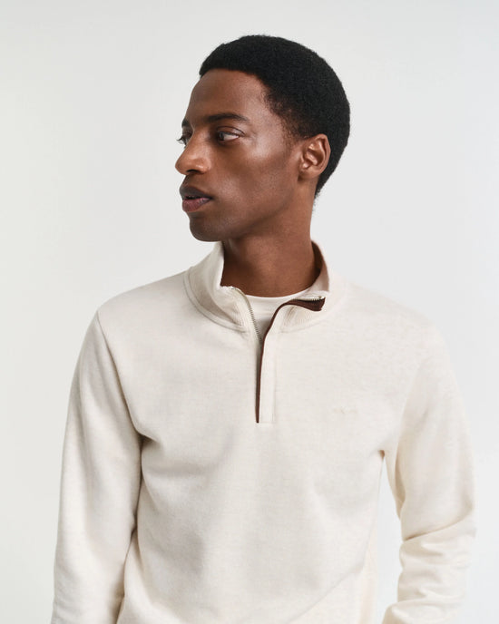 Beige herrtröja med halv dragkedja, lång ärm, klassisk stil, modell tittar åt sidan