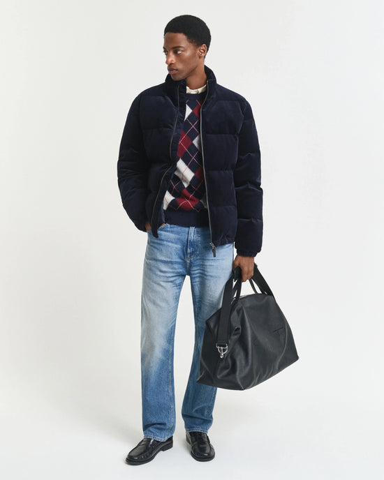 Mörkblå herr vinterjacka med rutor, jeans och svart väska, studiofoto