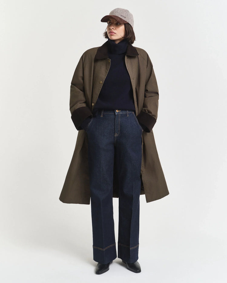 Olivgrön långrock herr, mörkblå polotröja, blå raka jeans, beige keps
