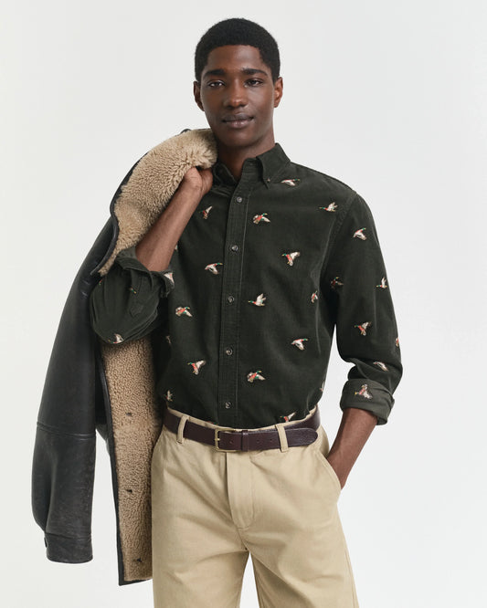 Modell i svart skjorta med fågelbroderier och beige byxor, herr skjorta