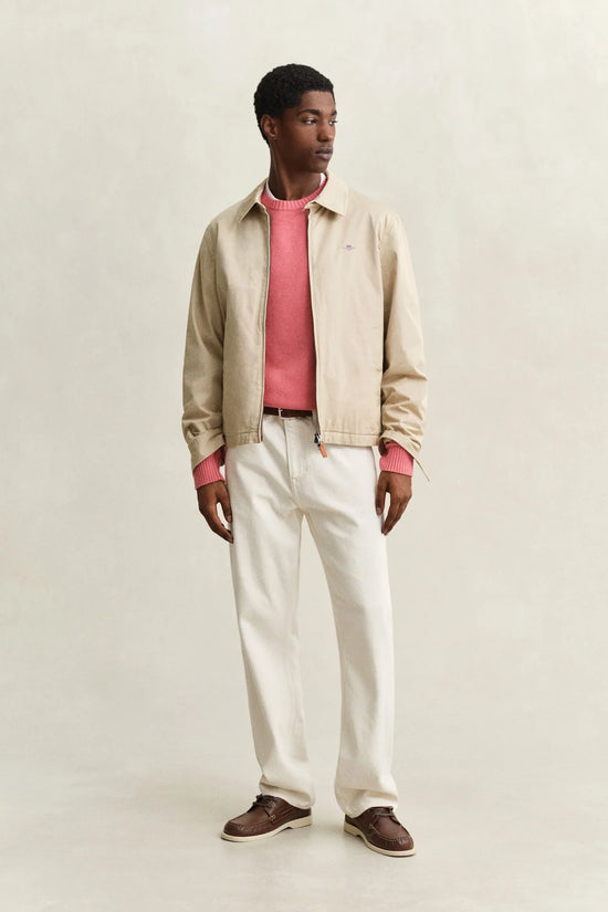 Beige harringtonjacka herr, rosa stickad tröja, vita jeans, bruna mockaskor