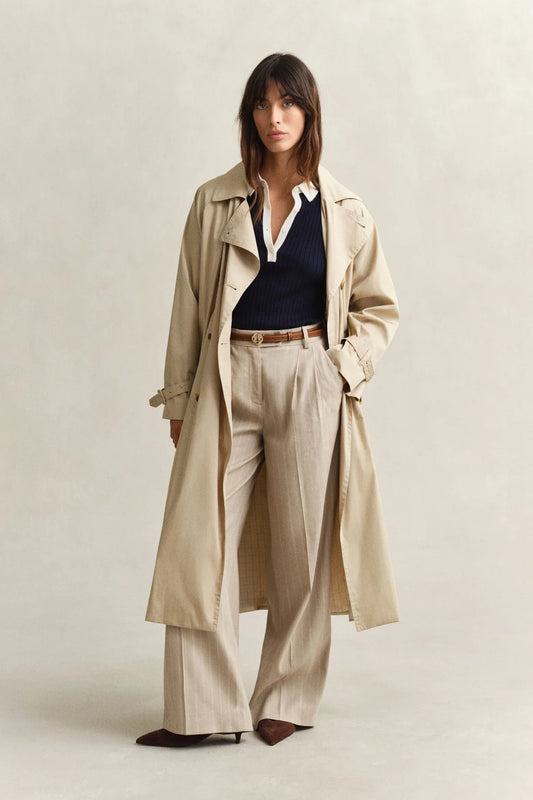 Beige trenchcoat, marinblå stickad tröja, ljusa kostymbyxor för dam