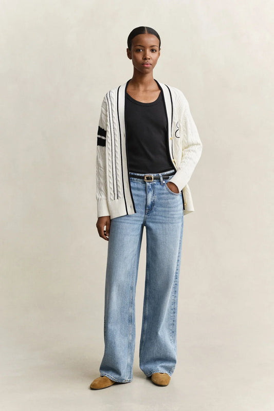 Vit kabelstickad kofta med svarta detaljer, svart t-shirt och ljusa jeans dam