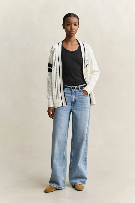Vit kabelstickad kofta med svarta detaljer, svart t-shirt och ljusa jeans dam