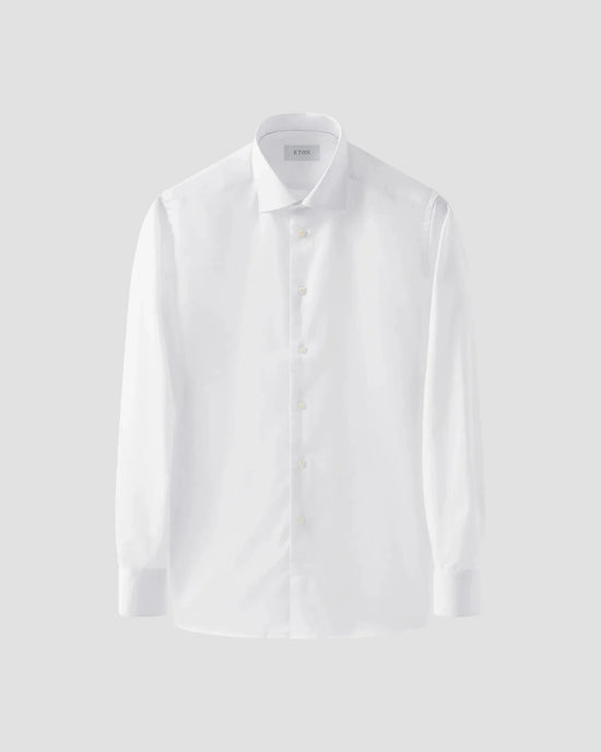 Klassisk vit herrskjorta i twill, långärmad med knappar och krage, mot ljus bakgrund.